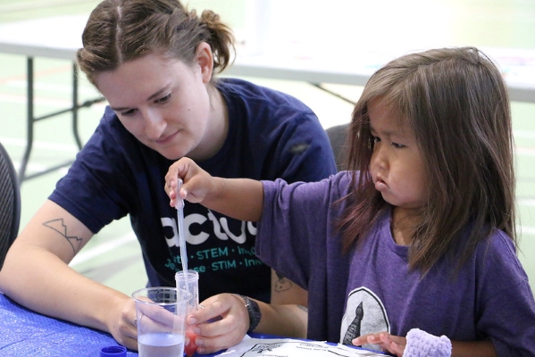 Photo of a young child and camp leader doing an experiment.