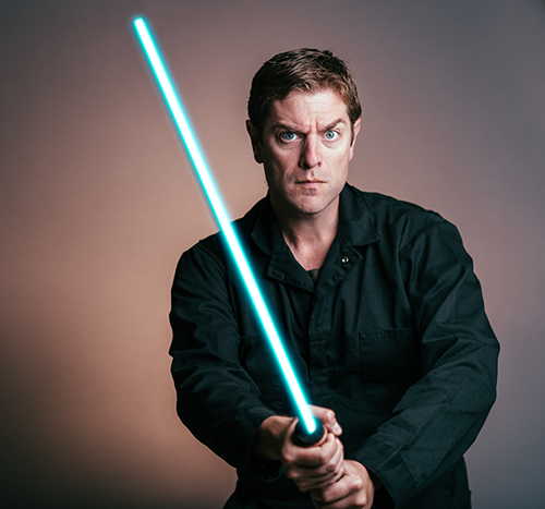 Charles Ross in character posing with a lightsaber,