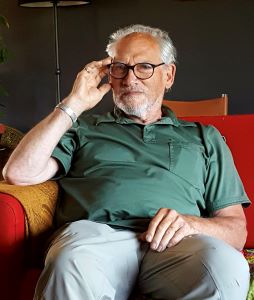 George Beer smiling sitting chair facing camera 