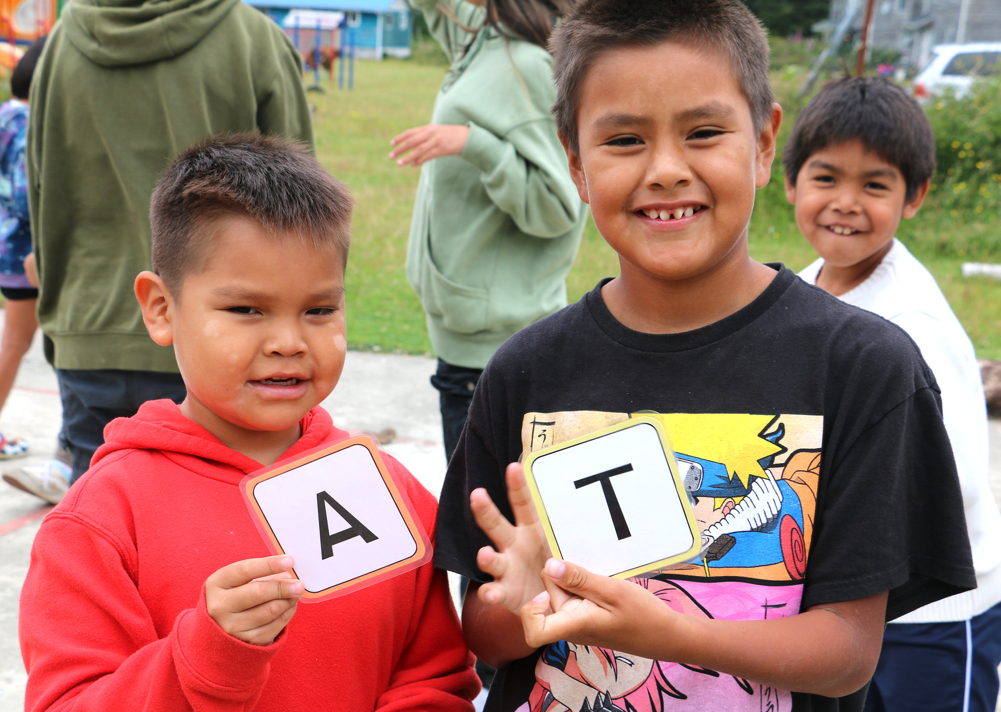 Two boys holding up letters 'A' and 'T'